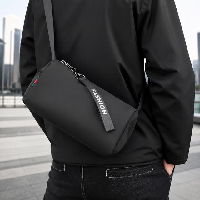 Queshark black waterproof nylon mini crossbody gym bag for men and women featuring a zipper tag with 'FASHION' lettering and adjustable shoulder strap.