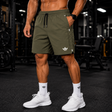 Olive green men's gym training shorts with breathable lightweight fabric, zip pockets, elastic drawstring waistband, and athletic fit for workouts, running, and fitness training.