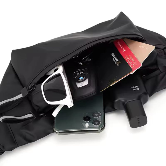 Black waist bag filled with daily essentials including a smartphone, perfume, sunglasses, and cards, showcasing interior storage capacity.